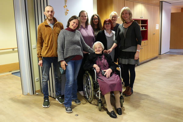 Gruppenfoto im Flur mit einer alten Frau im Rollstuhl