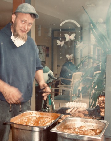 Mann mit Grillzange und Fleisch