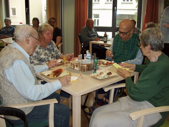 Speisesaal mit vielen älteren Menschen die frisch Gegrilltes essen