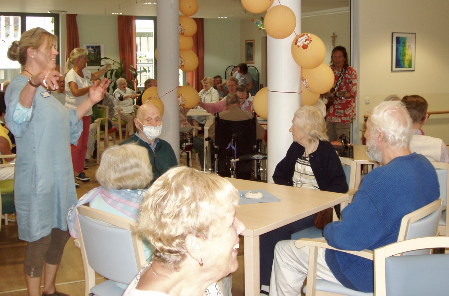 Speisesaal mit vielen älteren Menschen und Mitarbeitenden lachen