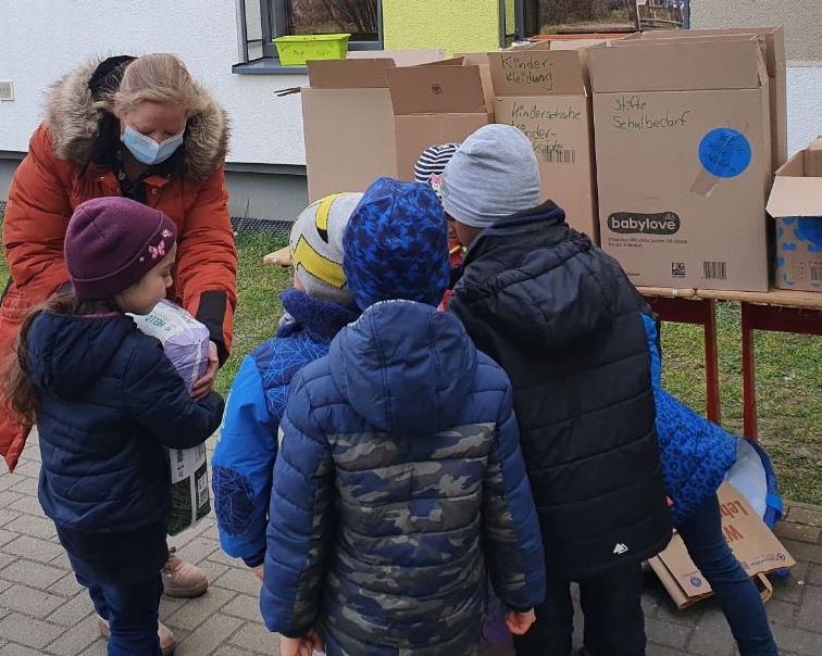 Kinder stehen vor Kartons mit Spenden Übergabe